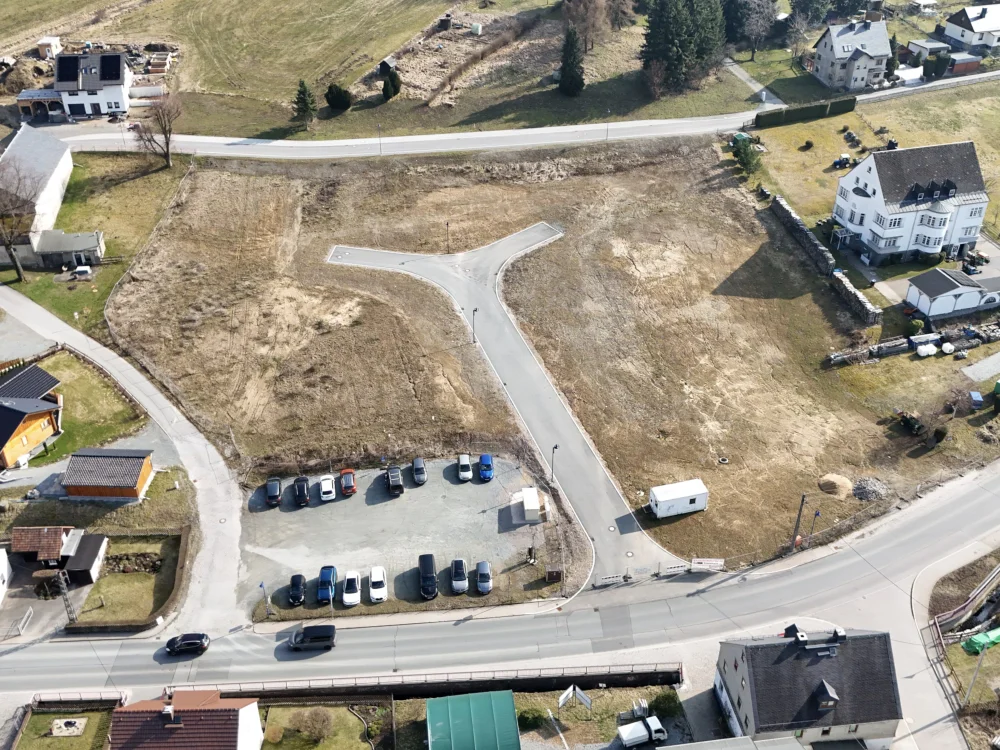 Drohnenaufnahme eines erschlossenen Baugebiets mit Straßenanbindung, Grundstücksflächen und vorbereiteter Infrastruktur für Neubebauung.