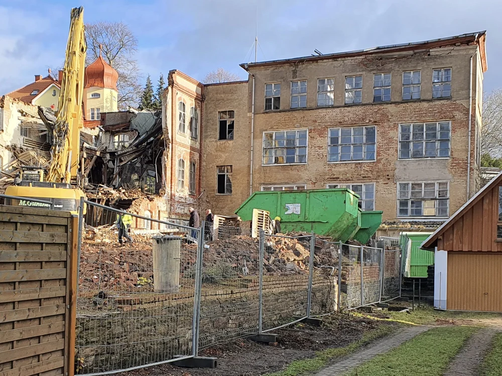 Abbrucharbeiten an altem Bestandsgebäude mit Bagger, Bauschutt und Container im Einsatz zur Grundstücksfreimachung für Neubauprojekt.