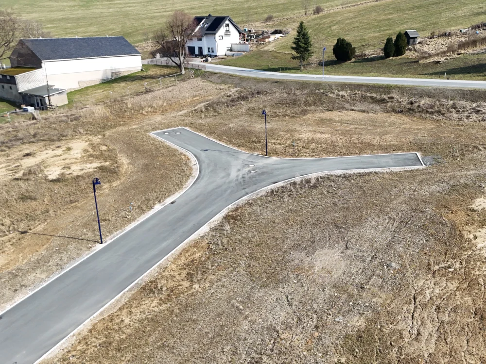 Erschlossenes Baugebiet mit neu angelegter Straße, Straßenbeleuchtung und vorbereiteten Grundstücksflächen für Wohnbebauung im ländlichen Raum.