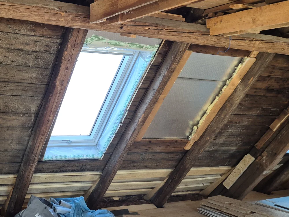 Dachausbau mit neu eingesetztem Dachfenster zwischen Holzbalken, inkl. Dämmung und Vorbereitung für modernen Innenausbau im Altbau.