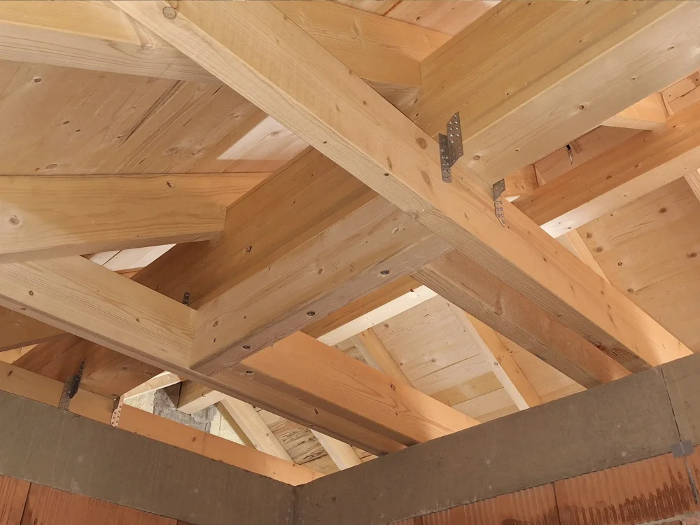 Sichtbarer Holzdachstuhl mit tragender Balkenkonstruktion und Verbindungselementen im modernen Holzbau, hochwertige Ausführung im Rohbau eines Wohngebäudes.