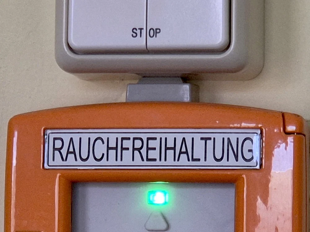 Rauchabzugsschalter zur Rauchfreihaltung mit STOP-Taster und Kontrollleuchte, Teil einer Rauch- und Wärmeabzugsanlage (RWA) im Gebäude für Brandschutz und Sicherheit.