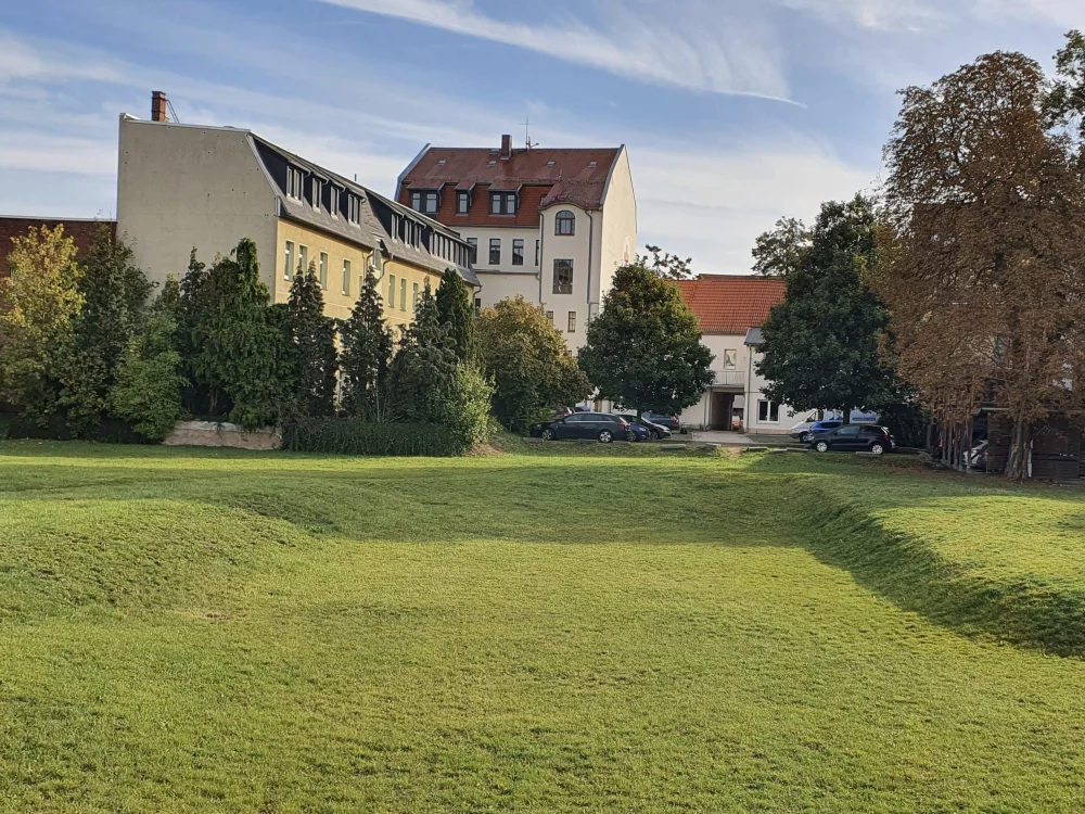 Grünfläche mit Hochwassermulde vor Wohngebäude, angelegte Rückhaltefläche zur Regenwasserableitung und Überflutungssicherung im Bereich Wasserbau und Landschaftsgestaltung.