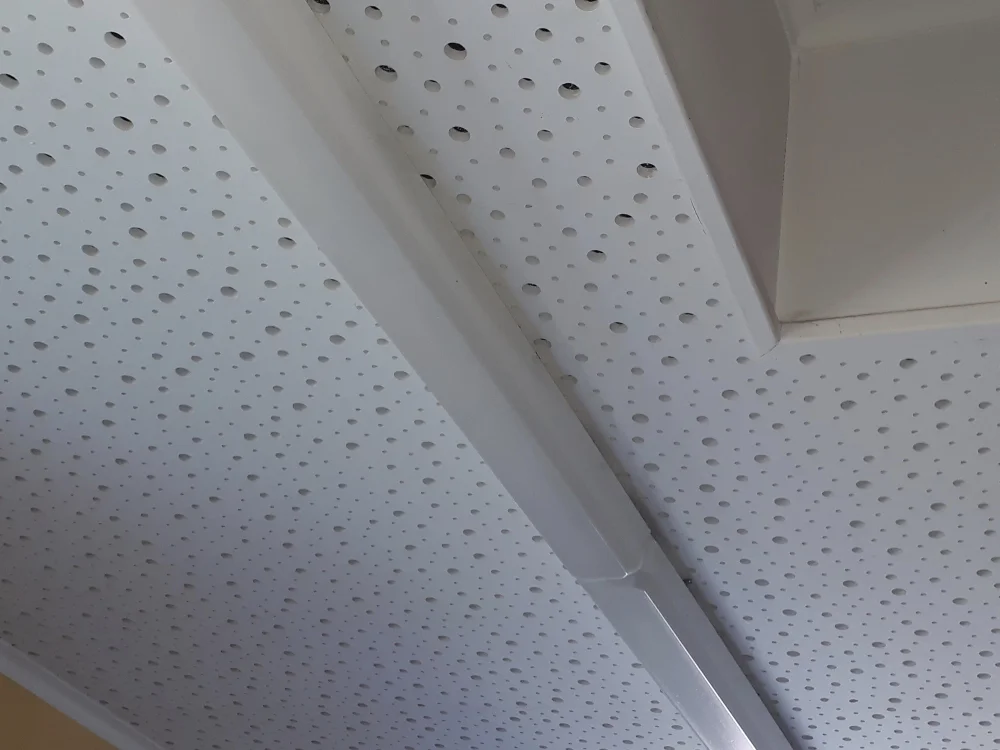 Akustikdecke mit gelochten Gipskartonplatten zur Schallabsorption im Innenausbau, kombiniert mit integrierter Beleuchtung für verbesserte Raumakustik.