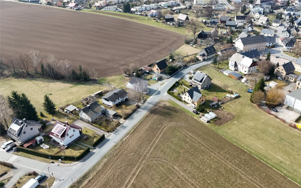 Drohnenaufnahme eines Wohngebiets an der Drebacher Straße mit Einfamilienhäusern, angrenzenden Ackerflächen und Straßenkreuzung in ländlicher Umgebung.